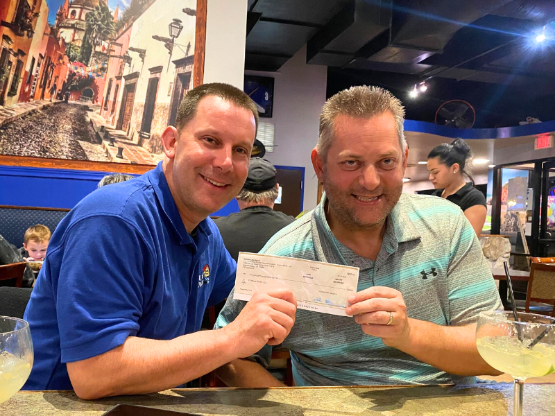 Scott with attendee holding a check